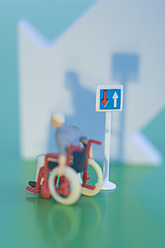Figurine in wheelchair with arrow sign on green background - ASF004687