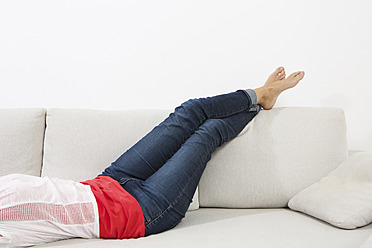 Germany, Berlin, Young woman lying on couch - SKF000981