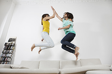 Deutschland, Berlin, Junge Frauen haben Spaß und springen auf der Couch - SKF001020