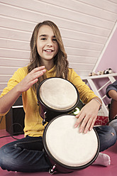 Girl playing drums, smiling, portrait - RNF001051