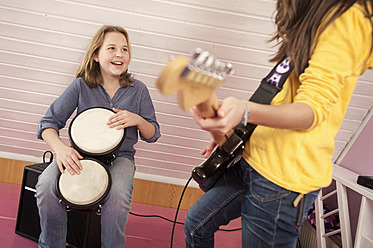 Mädchen spielen Gitarre und Schlagzeug, lächelnd - RNF001055