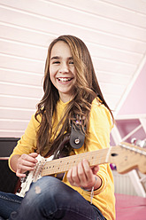 Girl playing guitar, smiling, portrait - RNF001062