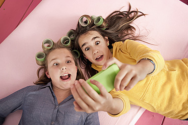 Mädchen mit Lockenwicklern fotografieren sich selbst mit dem Smartphone - RNF001075