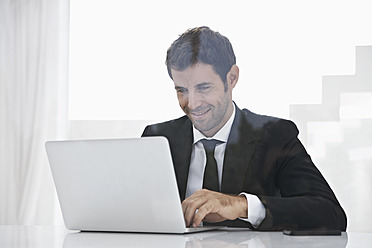 Spanien, Geschäftsmann mit Laptop, lächelnd - PDYF000300