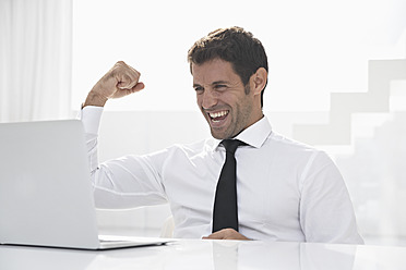 Spain, Businessman excited while looking laptop, smiling - PDYF000313