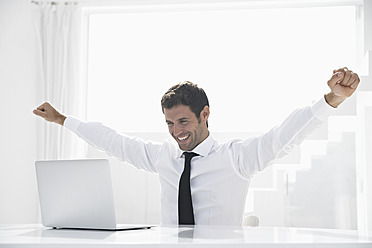 Spain, Businessman excited while looking laptop, smiling - PDYF000318