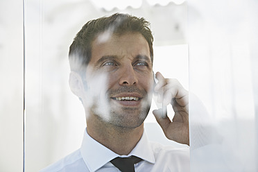 Spain, Businessman talking on mobile phone, smiling - PDYF000346