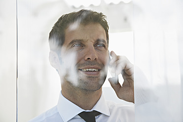 Spanien, Geschäftsmann im Gespräch mit Handy, lächelnd - PDYF000346
