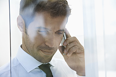 Spain, Businessman talking on mobile phone, smiling - PDYF000347