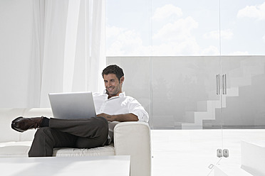 Spanien, Geschäftsmann mit Laptop, lächelnd - PDYF000365