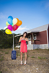 USA, Texas, Junge Frau mit Koffer und Luftballons - ABAF000482