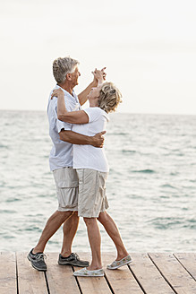 Spain, Senior couple dancing on jetty at the sea - JKF000013