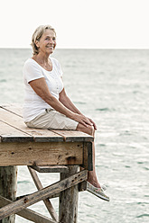 Spanien, Ältere Frau sitzt auf Steg am Meer - JKF000035