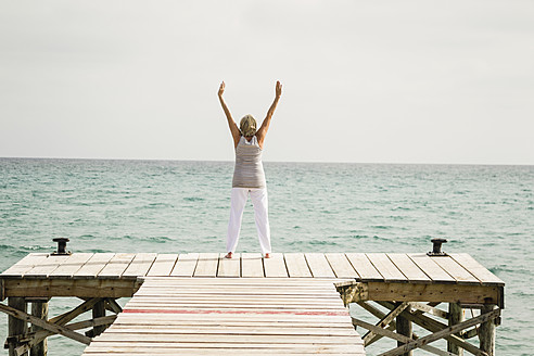 Spain, Senior woman exercising on jetty at the sea - JKF000040