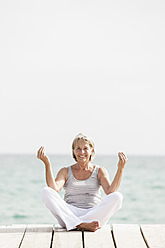 Spanien, Ältere Frau beim Yoga auf dem Steg am Meer - JKF000042