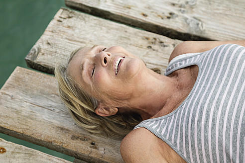 Spain, Senior woman relaxing on jetty at the sea - JKF000052