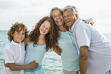 Spanien, Großeltern mit Enkelkindern am Meer, lächelnd, Porträt - JKF000060