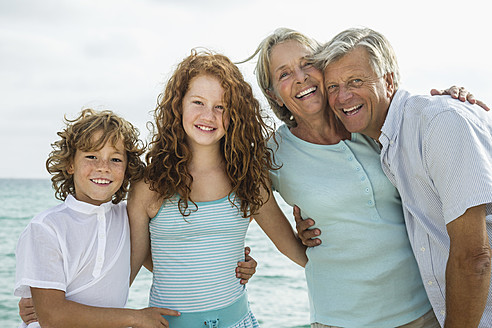 Spanien, Großeltern mit Enkelkindern am Meer, lächelnd, Porträt - JKF000061