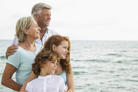 Spanien, Großeltern mit Enkelkindern am Meer, lächelnd, Porträt, lizenzfreies Stockfoto