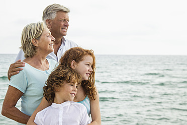 Spanien, Großeltern mit Enkelkindern am Meer, lächelnd, Porträt - JKF000064