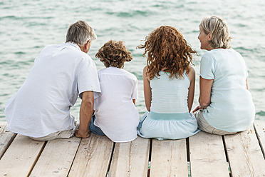 Spain, Grandparents with grandchildren sitting on jetty - JKF000068