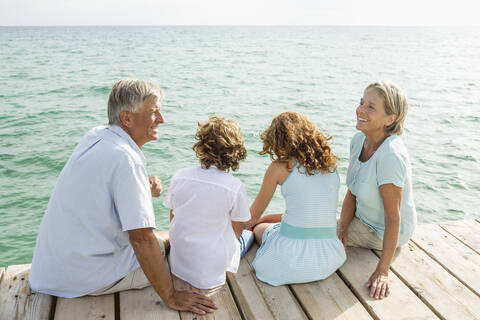 Spain, Grandparents with grandchildren sitting on jetty stock photo