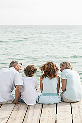 Spain, Grandparents with grandchildren sitting on jetty - JKF000070