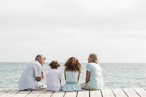 Spain, Grandparents with grandchildren sitting on jetty - JKF000071