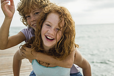 Spain, Girl giving piggy ride to boy, smiling - JKF000077