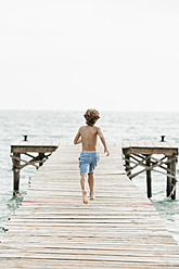 Spanien, Junge läuft auf Steg am Meer - JKF000078