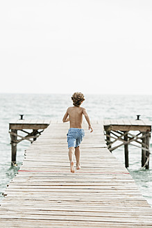 Spain, Boy running on jetty at the sea - JKF000078