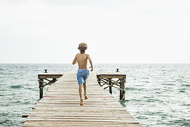 Spanien, Junge läuft auf Steg am Meer - JKF000079