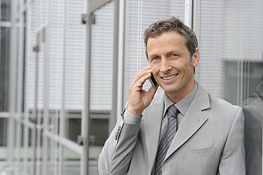 Europe, Germany, Bavaria, Businessman talking on mobile, smiling, portrait - CRF002212