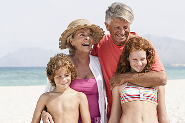Spain, Grandparents with grandchildren having fun at beach, smiling - JKF000086