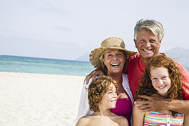 Spain, Grandparents with grandchildren having fun at beach, smiling - JKF000087