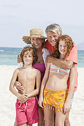 Spain, Grandparents with grandchildren having fun at beach, smiling - JKF000088