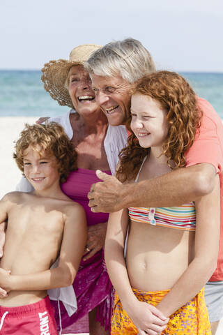 Spanien, Großeltern mit Enkelkindern haben Spaß am Strand, lächelnd, lizenzfreies Stockfoto