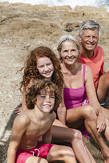 Spanien, Großeltern mit Enkelkindern am Strand sitzend, lächelnd, Porträt - JKF000092