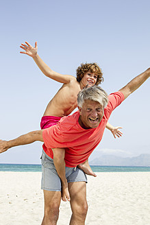 Spain, Grandfather giving piggyback ride to grandson, smiling - JKF000106