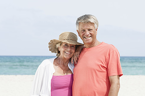 Spanien, Seniorpaar am Strand stehend, lächelnd, Porträt - JKF000110