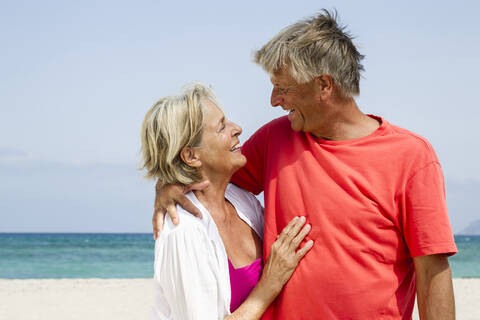 Spanien, älteres Paar am Strand, lächelnd, lizenzfreies Stockfoto