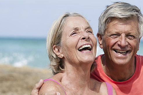 Spanien, Seniorpaar am Strand, lächelnd - JKF000119