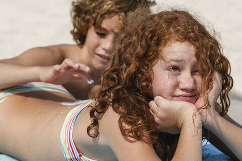Spain, Brother drawing on sisters back with suncream stock photo