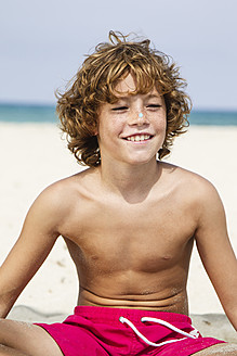 Spain, Boy sitting on beach, smiling - JKF000140