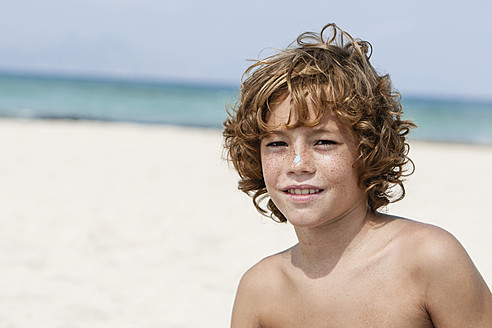 Spain, Boy sitting on beach, smiling - JKF000141