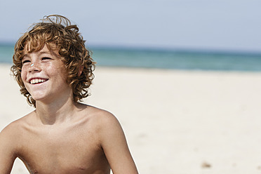 Spanien, Junge sitzt am Strand, lächelnd - JKF000142