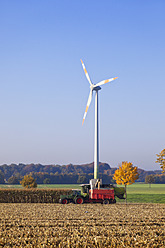 Deutschland, Nordrhein-Westfalen, Blick auf Windkraftanlage mit Erntefahrzeug bei Coesfeld - MSF002819