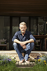 Germany, Berlin, Mature man relaxing on terrace, smiling, portrait - SKF001093