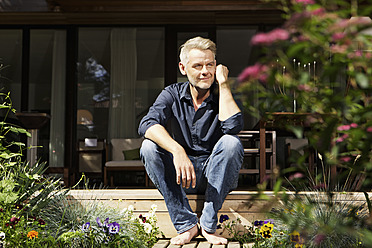 Germany, Berlin, Mature man relaxing on terrace, smiling - SKF001095