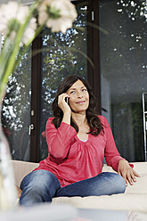 Germany, Berlin, Mature woman talking on mobile phone, smiling - SKF001114